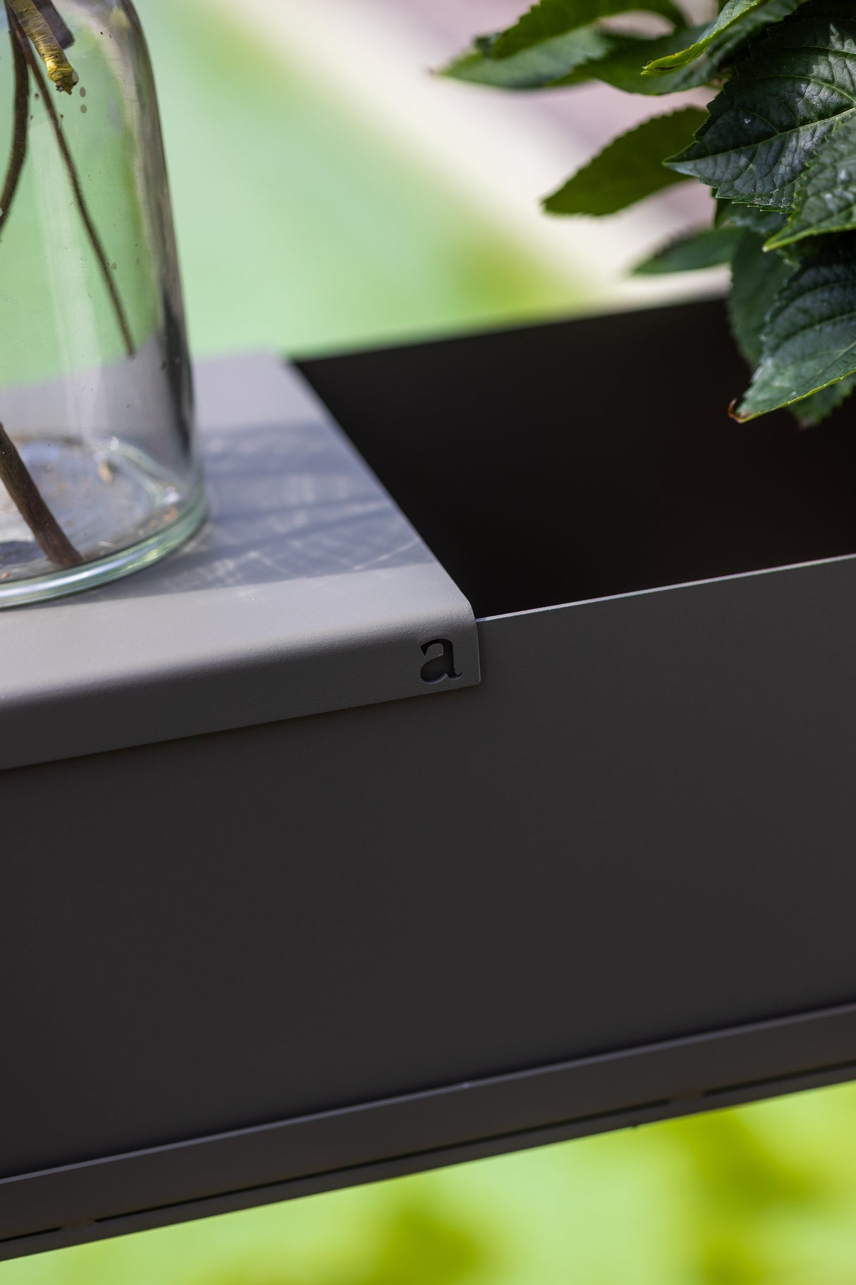 Detailansicht der TABLA - Aufsatzplatte mit eingelasertem Logo, passend für Pflanzgefäße im Garten oder auf der Terrasse.