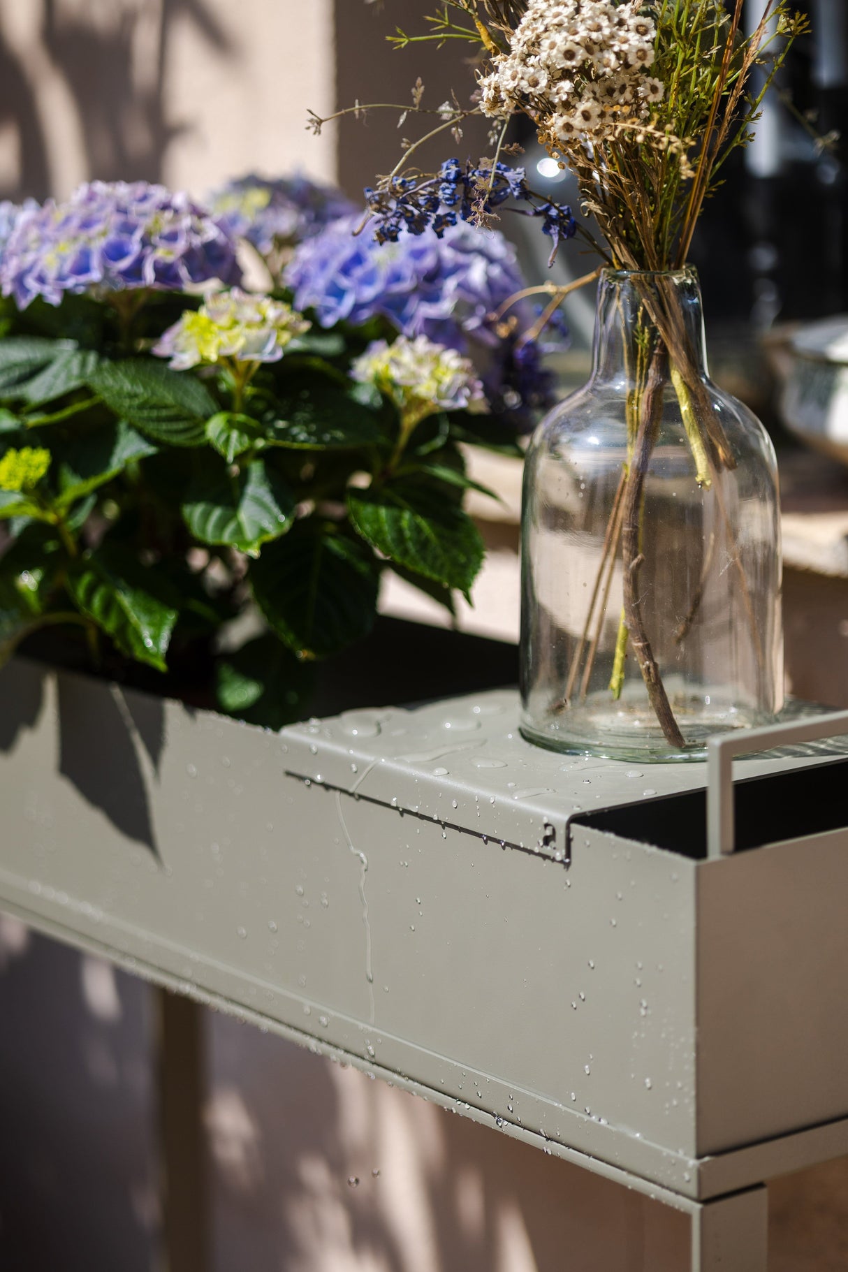Detailansicht des VERDE - Pflanztrogs mit Wasserperlen auf der Oberfläche, wetterfester Edelstahl für langlebige Gartennutzung.