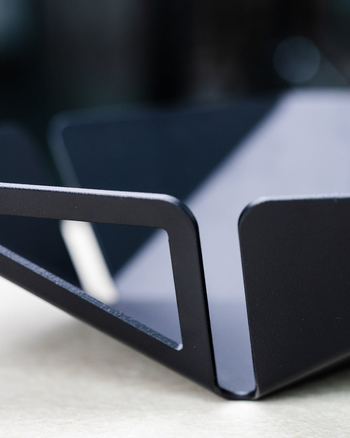 Detailansicht der PRISMA - Obstschale mit präzise gefertigtem Griff aus pulverbeschichtetem Edelstahl in Schwarz.