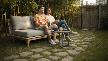 Ein elegantes, minimalistisches Outdoor-Sofa lädt ein zum Verweilen – ein Pärchen genießt gemeinsam die entspannte Atmosphäre ihres kleinen Gartens.
