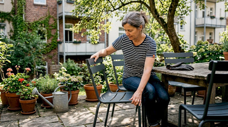 Eine Frau richtet die Gartenmöbel auf der Terrasse ordentlich her.