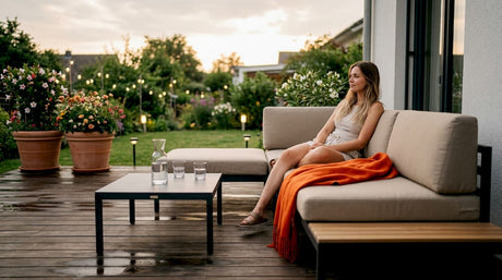 Eine Frau genießt entspannte Stunden auf ihrer Terrasse und macht es sich auf modernen, modularen Gartenmöbeln bequem.