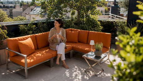 Eine Frau genießt entspannte Momente auf modularen Gartenmöbeln auf ihrem städtischen Balkon.