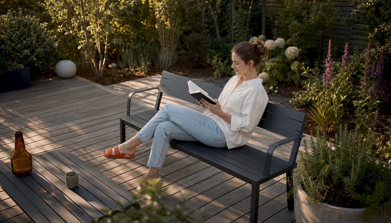 Eine Frau genießt die Ruhe auf ihrer modern gestalteten Terrasse im Garten.