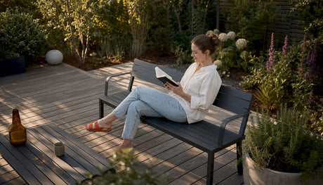 Eine Frau genießt die Ruhe auf ihrer modern gestalteten Terrasse im Garten.