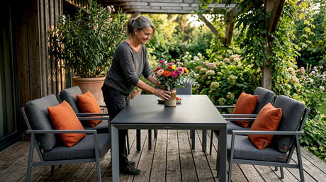 Eine Frau bereitet auf ihrer sonnigen Terrasse den Tisch für einen gemütlichen Nachmittag vor.