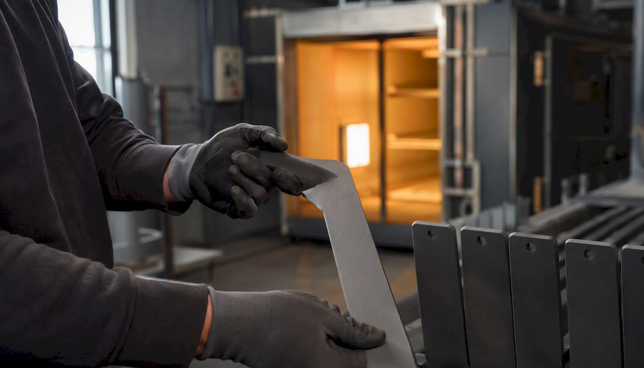 Pulverbeschichtetes Metall wird im Ofen gehärtet – bitte Hände fernhalten.
