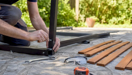 Mit geschickten Händen wird draußen ein Terrassentisch zusammengebaut.