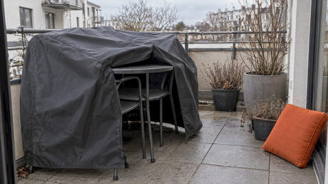 Mit Abdeckplanen geschützte Balkonmöbel auf einem Stadtbalkon